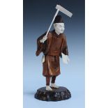 A Japanese carved ivory and boxwood okimono figure, Meiji period, modelled as a standing farmer