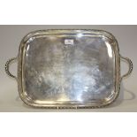 A George V silver two handled tray of rectangular form, with gadrooned rim and scroll handles,