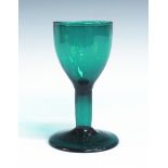 A green tinted wine glass, mid-18th Century, the pointed rounded funnel bowl raised on a hollow