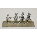 A 20th Century Dutch silver model of four children on ice skates holding onto a pole, on a