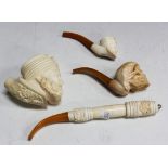 A 20th Century meerschaum pipe, carved in the form of a human skull, together with two other similar