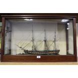 A 19th Century painted wood and glass model of a three masted gunboat, mounted upon a glass bordered