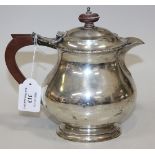 A George V silver hot water pot of baluster form with foliate rim, on an oval foot, Birmingham