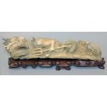 A Chinese ivory tusk carving, late 19th/early 20th Century, carved and pierced as a dragon on a