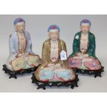 A set of three Chinese porcelain figures of Buddha, 20th Century, each modelled seated in