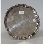 A silver circular salver with piecrust rim, on four scroll feet, Sheffield 1972 by Oliver & Bower