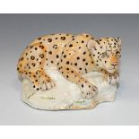 A Miranda C. Smith pottery model of a recumbent leopard on a rocky base, painted signature to side