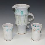 An Ian Godfrey stoneware studio pottery jug and two beakers, circa 1980, each white glazed, the