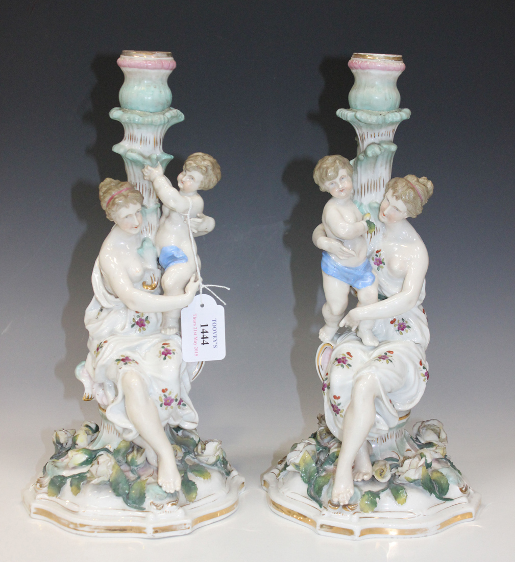 A pair of Dresden porcelain Meissen style candlesticks, late 19th Century, each modelled as a maiden