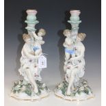 A pair of Dresden porcelain Meissen style candlesticks, late 19th Century, each modelled as a maiden