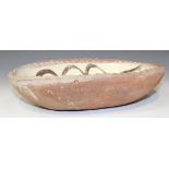 An early Winchcombe Pottery red earthenware oval slipware dish, possibly by Michael Cardew, the