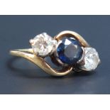 A gold ring mounted with a central circular cut sapphire between two circular cut diamonds in a
