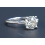 An 18ct white gold and diamond ring, claw set with a circular cut diamond between tapering