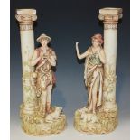 A pair of Royal Dux porcelain figural candlesticks, early 20th Century, each Ionic column flanked by