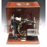 A 19th Century Willcox & Gibbs black enamelled cast iron sewing machine, mounted on a mahogany