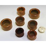 A group of seven turned treen cylindrical boxes with glass inset lids, together with a turned bone