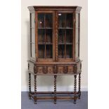 A George V oak display cabinet, the moulded pediment above a pair of glazed panel doors and a pair