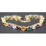 A gold and vari-coloured gemstone bracelet, claw set with a row of oval cut gem stones, including