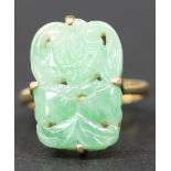 An 18ct gold ring, claw set with a rectangular jade, carved and pierced with fruit and leaves,