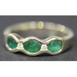 An 18ct white gold, emerald and diamond five stone ring, mounted with three oval cut emeralds