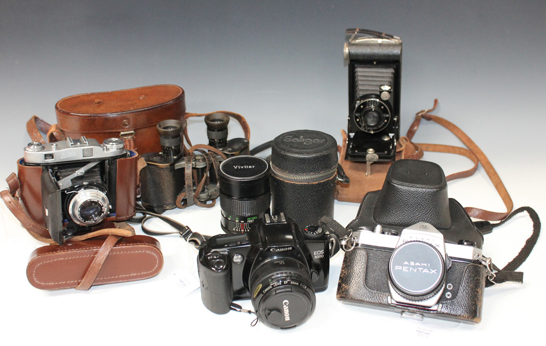 A collection of assorted cameras and accessories, including a Canon EOS 3000 camera with 50mm