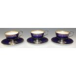 A set of three silver mounted Mintons blue glazed bone china teacups and saucers, each pierced