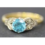 A gold, platinum, blue zircon and diamond ring, claw set with the circular cut blue zircon between