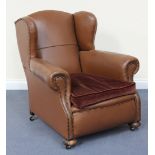 A George V wing back club armchair, upholstered in brown leatherette, on cup feet and castors, width
