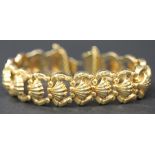 A gold bracelet, the links formed as a row of stylized shells, on a snap clasp with a safety