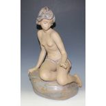A Lladro Gres figure of a semi-clad young lady kneeling upon a rock, printed factory mark to base,