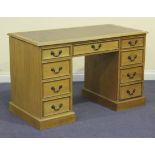 A 20th Century oak twin pedestal desk with an inset tooled brown leather top above an arrangement of