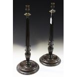 A pair of early 20th Century George III style mahogany candlesticks, the cast brass tops above