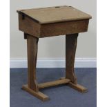 A 20th Century oak school desk with hinged writing slope, on shaped supports, width approx 56cm.