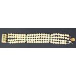 A four row bracelet of cultured pearls on a gold and green gem set clasp, length approx 19cm.