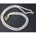 A two row necklace of uniform cultured pearls, on a 9ct gold and diamond set clasp, decorated with