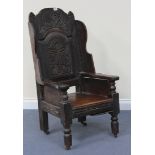 A 17th Century and later oak Wainscot chair, the panelled back carved in relief with flowers and