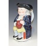 A Staffordshire pottery toby jug, 19th Century, modelled seated wearing a black tricorn hat, holding