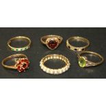 A 9ct gold and garnet set nine stone cluster ring, a gold ring, mounted with an oval cut peridot,