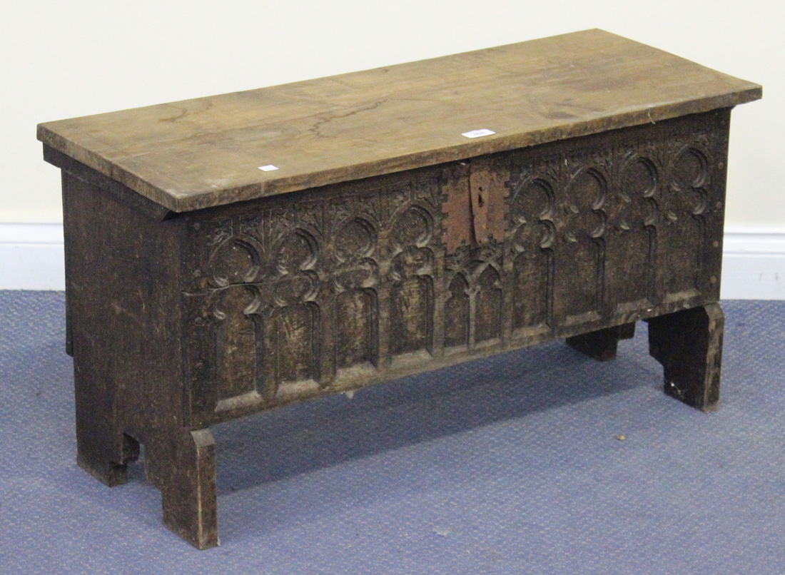 A 20th Century Gothic Revival oak six-plank coffer, the hinged lid above a carved tracery front,