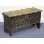 A 20th Century Gothic Revival oak six-plank coffer, the hinged lid above a carved tracery front,