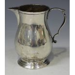 A George V silver cream jug of baluster form with scroll handle, on a circular foot, London 1934