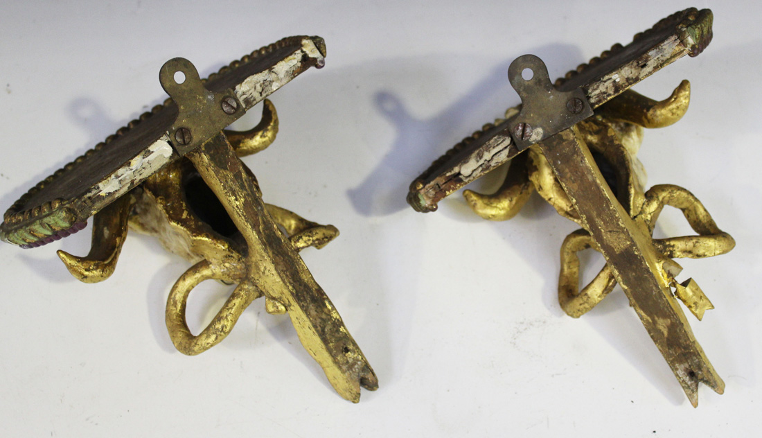 A pair of late 19th Century cream and gilt painted wall brackets, each with a ram's mask and tied - Image 2 of 2