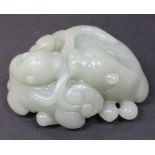 A Chinese celadon jade two dog pendant, 20th Century, carved as two dogs chewing on a lingzhi