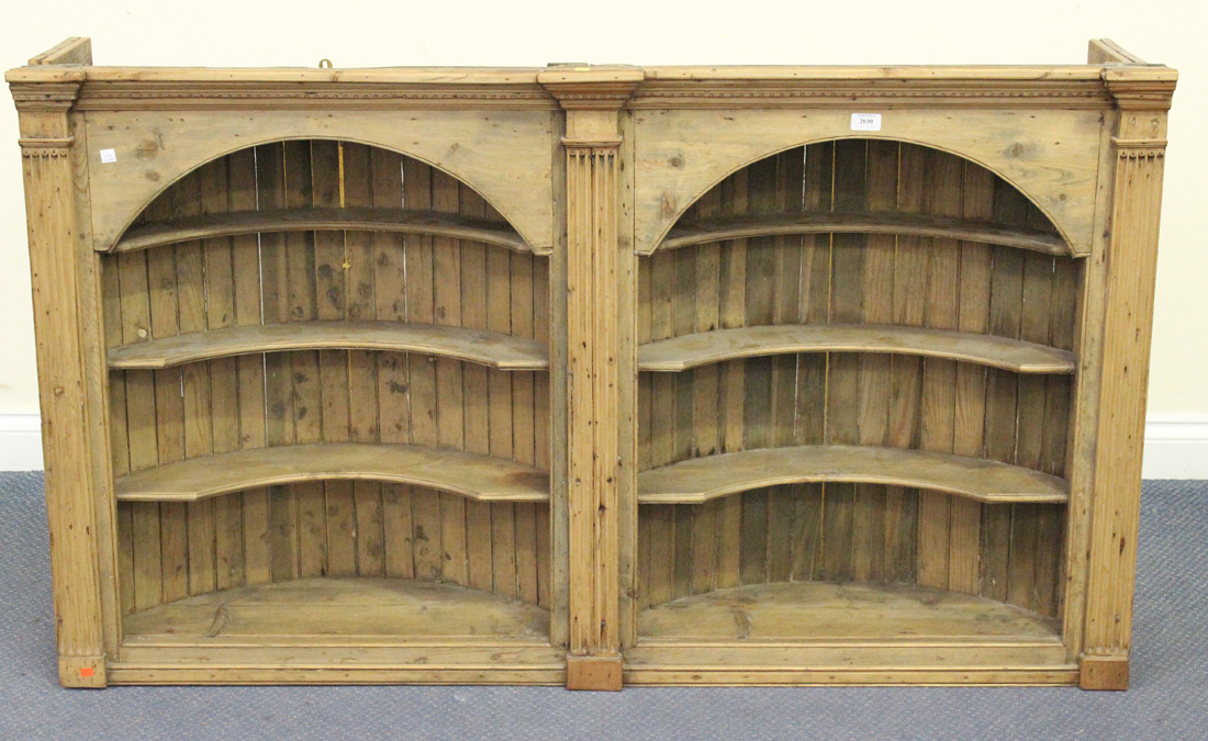 A George III and later pine arched two-section wall shelf with a moulded pediment and stop fluted
