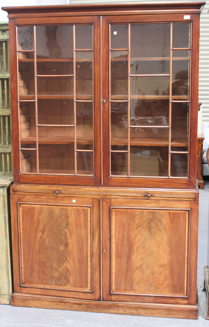 A late George III mahogany bookcase cabinet, the moulded pediment above a pair of astragal glazed