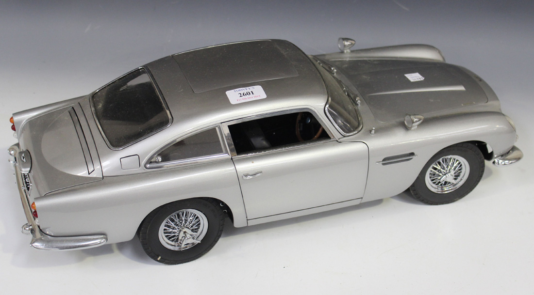 A 1:8 scale replica model of James Bond's Aston Martin DB5, together with related magazine issues.