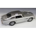 A 1:8 scale replica model of James Bond's Aston Martin DB5, together with related magazine issues.