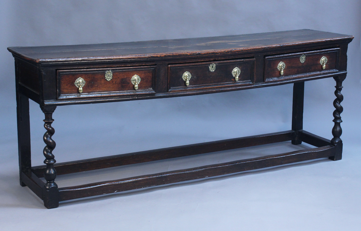 A late 17th/early 18th Century oak dresser base, the two-plank top above three frieze drawers with