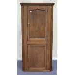 An 18th Century oak corner cupboard, the moulded pediment above two panelled doors revealing