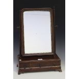 A George III mahogany swing frame mirror, the base fitted with three shaped drawers, on ogee bracket